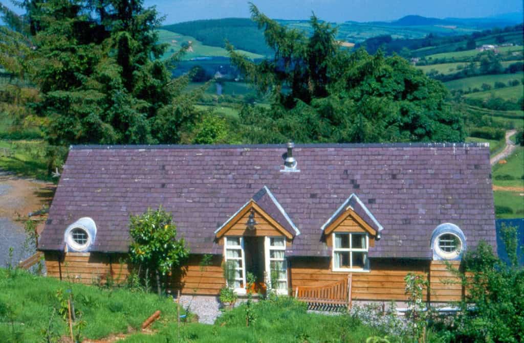 Charming countryside cottage with wooden exterior and scenic landscape.