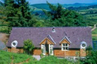 Charming countryside cottage with wooden exterior and scenic landscape.